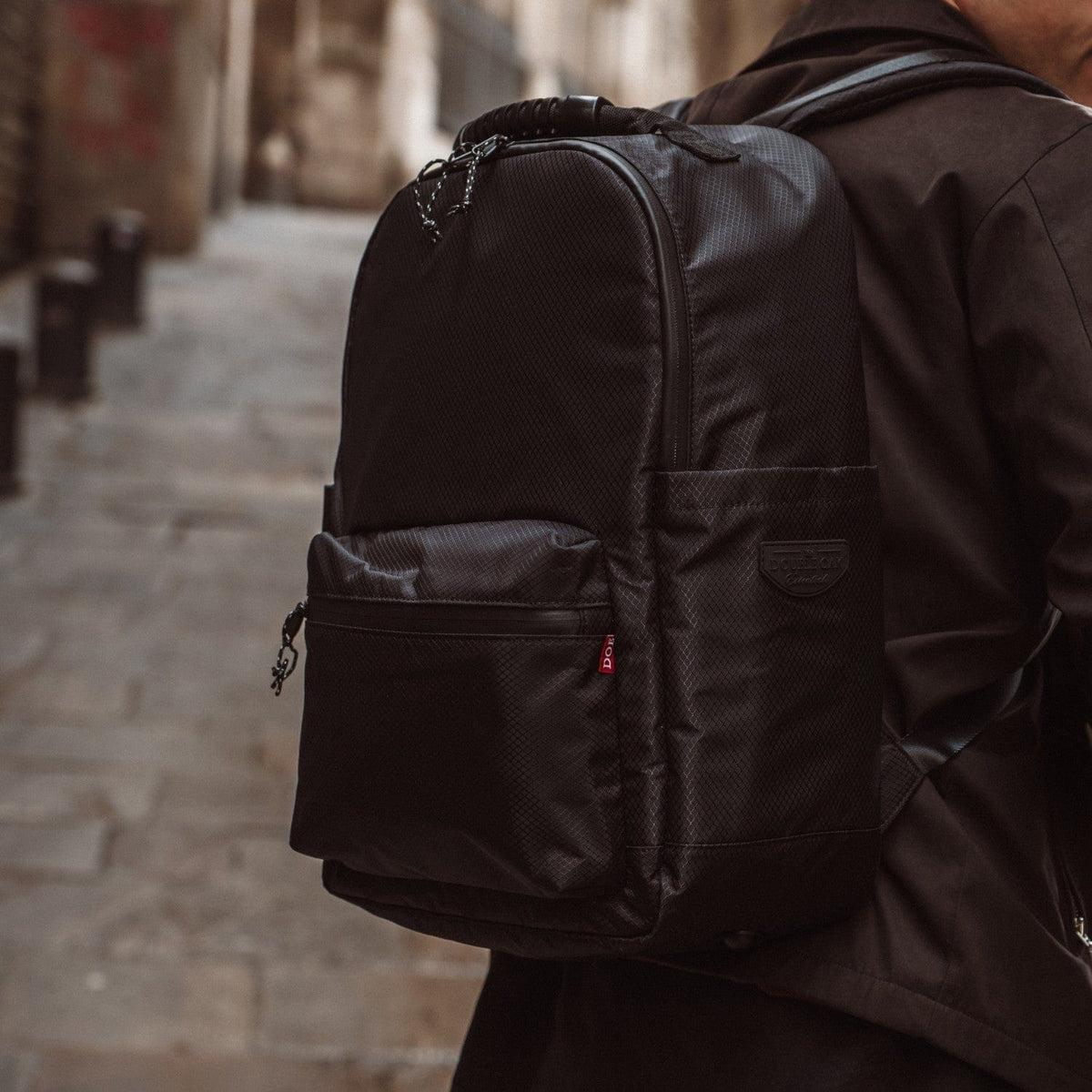 Black fabric backpack with front zip pocket and top handle straps
