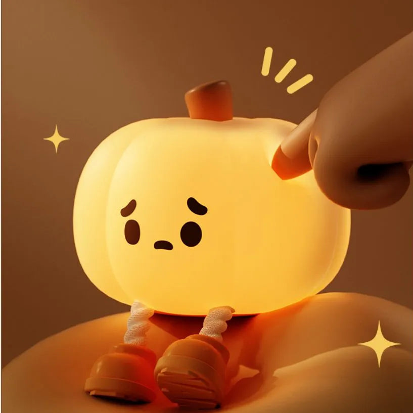 Silicone pumpkin night light with sad face, raised hands pose, warm orange glow