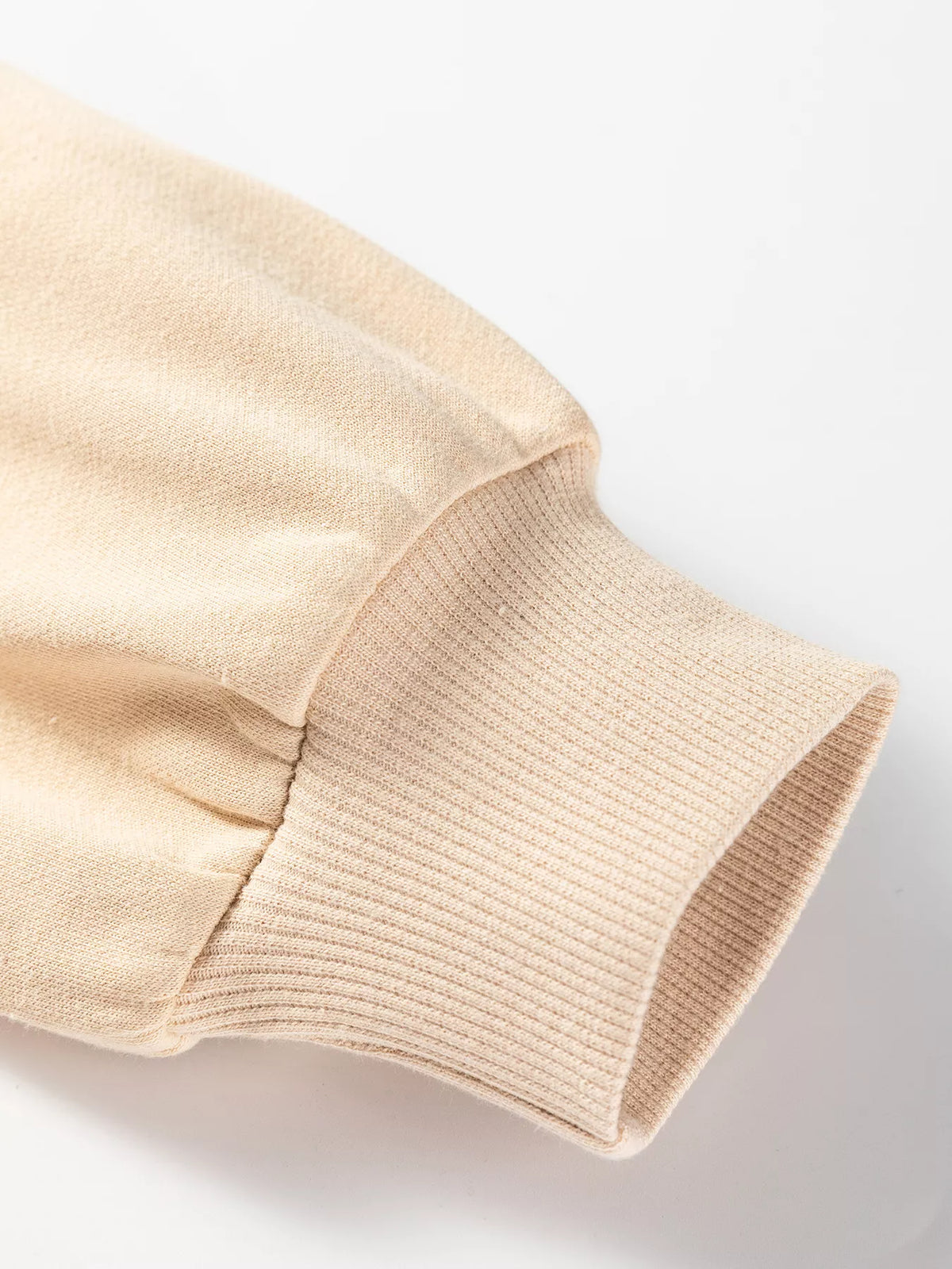 Beige sweatshirt sleeve cuff with gathered seam at drop shoulder