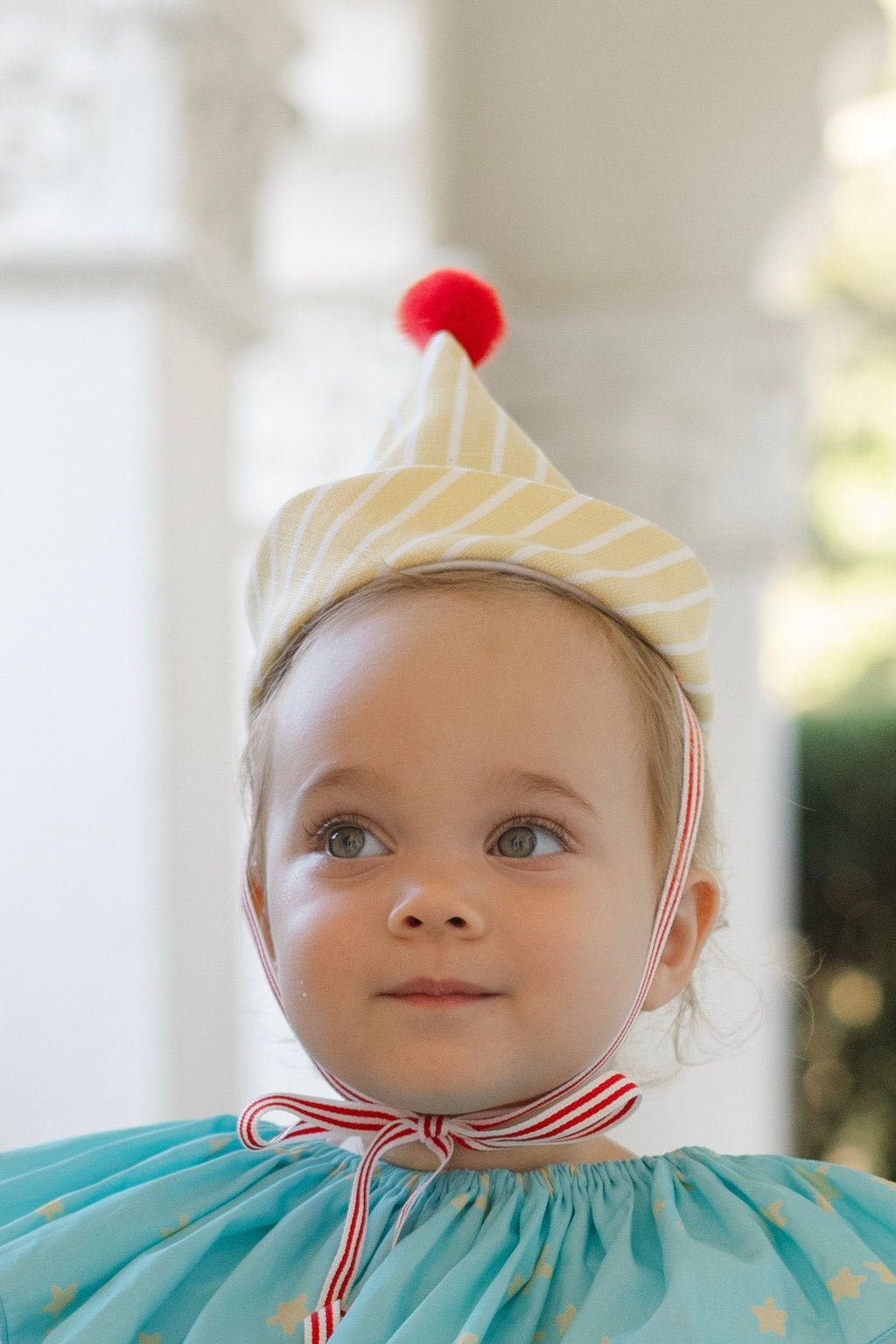 Clown costume close-up: yellow striped hat with pom, blue ruffled collar, star-print top