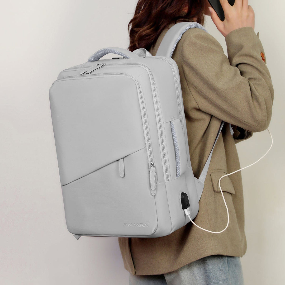 Storm gray backpack worn by person with charging cable passing from side port