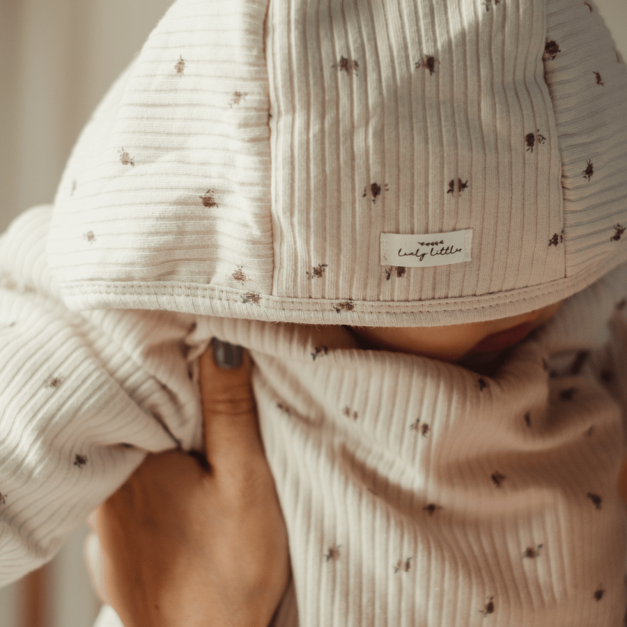 Ribbed hood and front on baby jacket in light pink with tiny speckle dot pattern