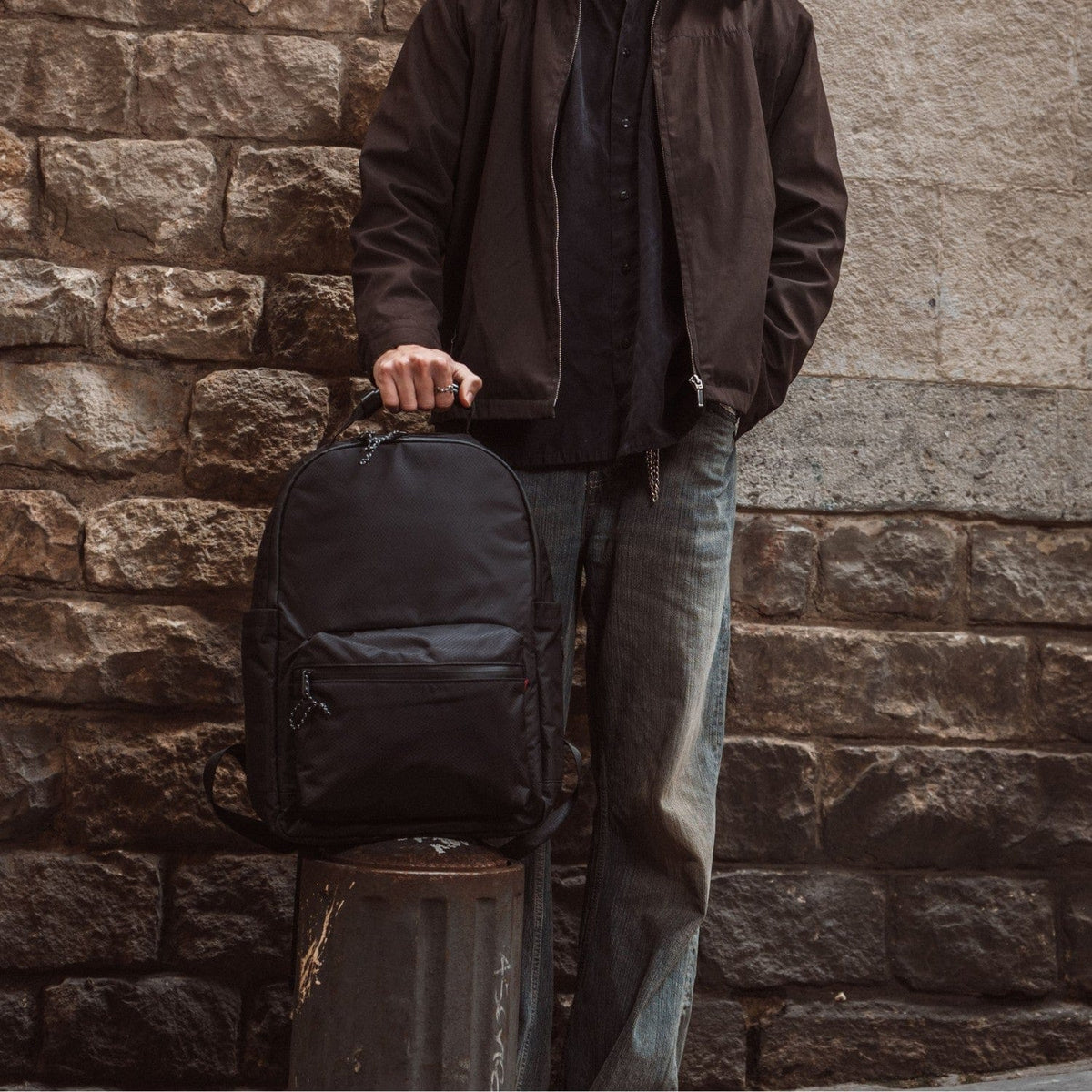 Black backpack with top handle, front zip pocket, and flap closure