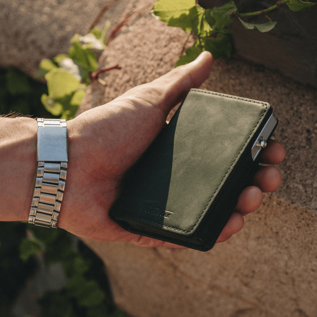 Dark green bifold wallet held open, showing interior card pocket and lining