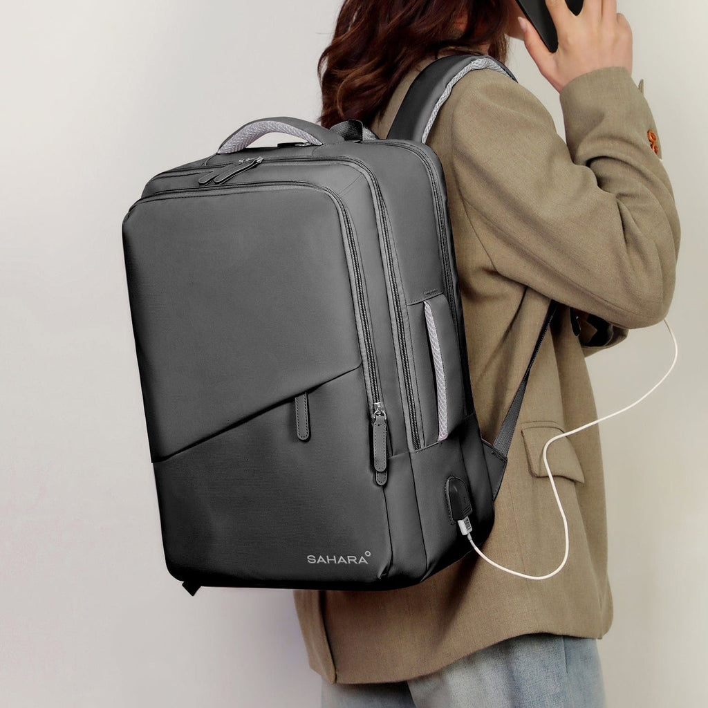 Gray laptop travel backpack worn on back with padded straps and front zip pocket.