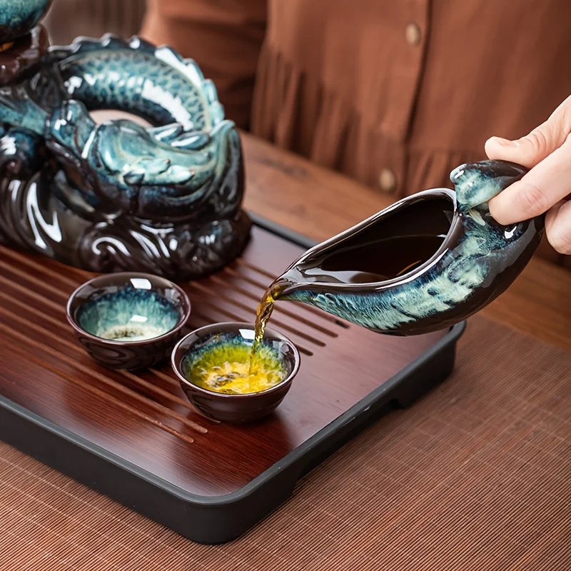 Ceramic dragon teapot pouring into a small cup, teal glazed spout over tray