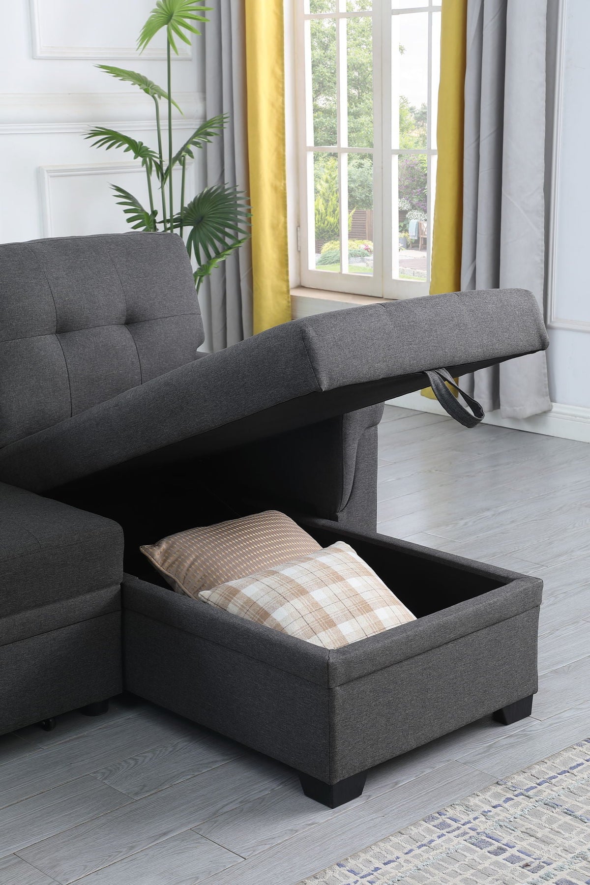 Dark gray sectional sofa corner with pull-out storage compartment and tufted seating.