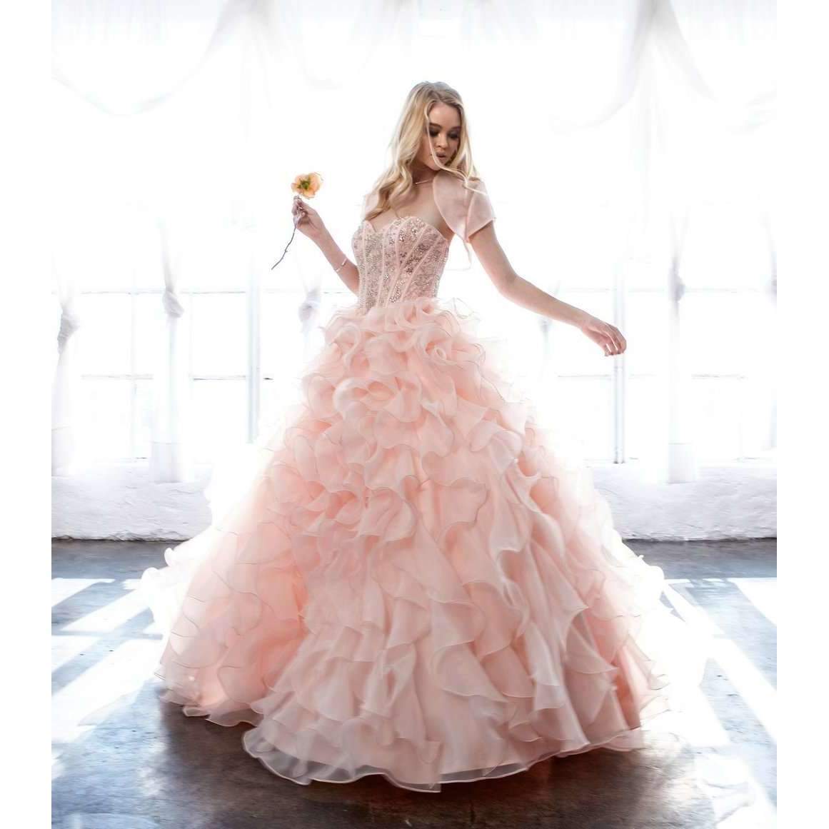 Pink ball gown with beaded corset top and layered organza ruffle skirt, standing pose