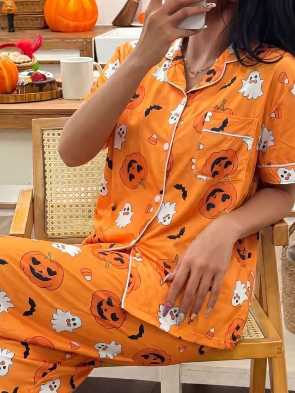 Orange Halloween pajama set with pumpkin and ghost prints, short-sleeve button-front top and pants