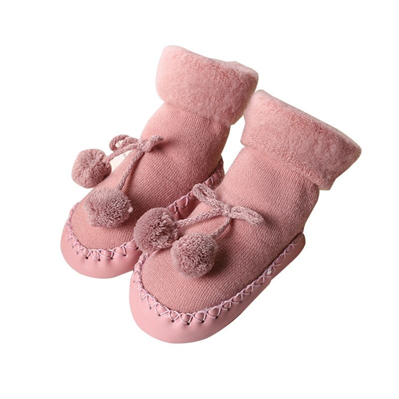 Pair of baby socks in rose pink with pom-pom bows and stitched edges