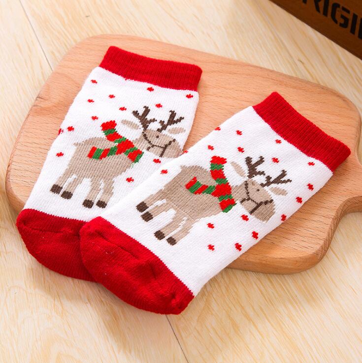 Children's cotton Christmas socks with reindeer face and red cuff on wood