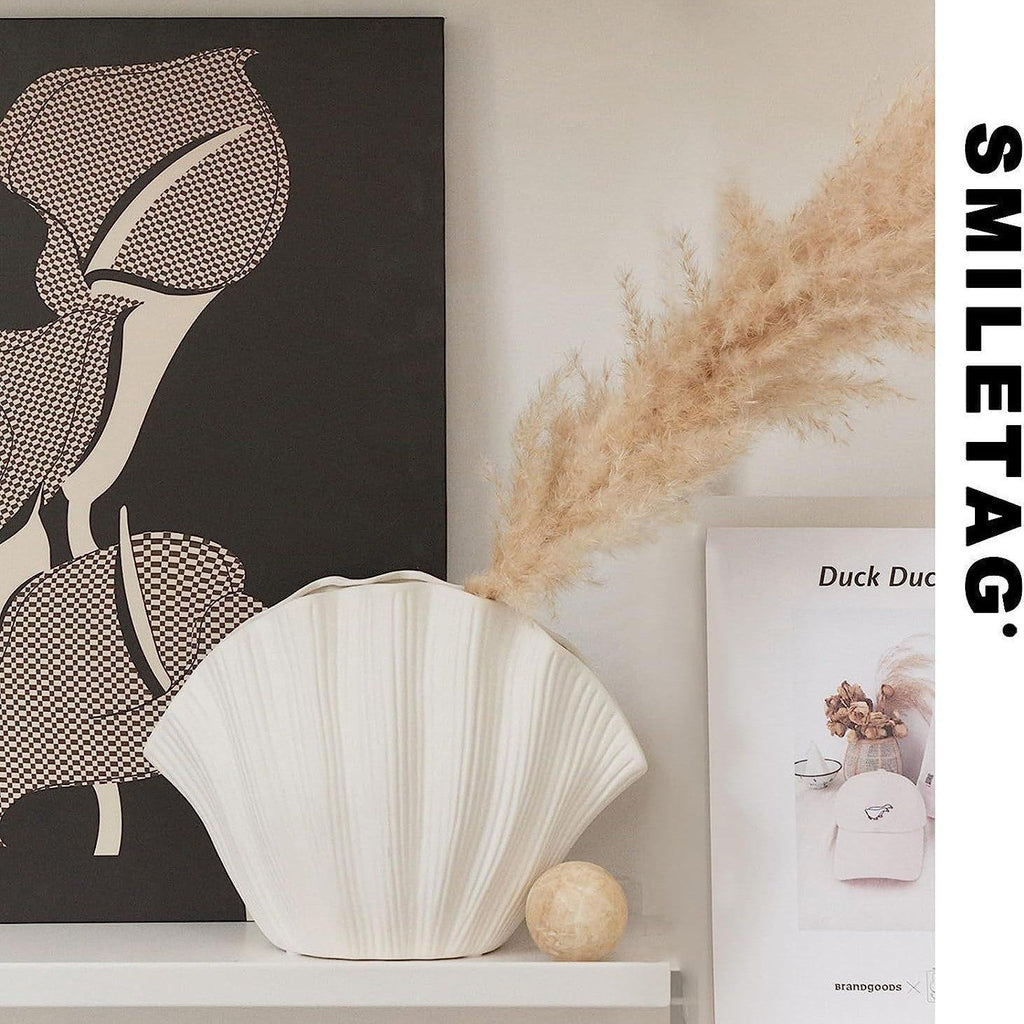 White ribbed shell-shaped ceramic vase with dried stems for decorative flowers