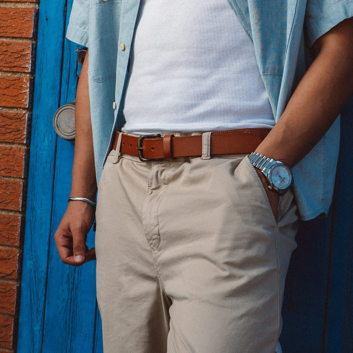Brown leather stretch belt with silver buckle, worn with light trousers