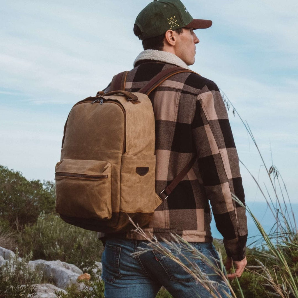 Sand waxed canvas backpack with front and side pockets, worn on a person