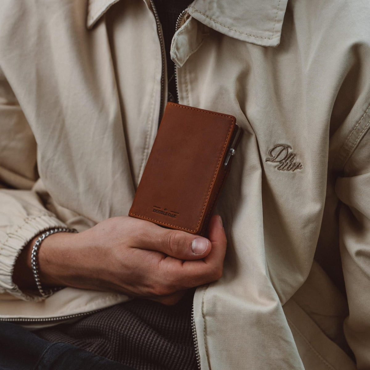 Brown leather bifold wallet in jacket pocket, slim profile with stitched edges.