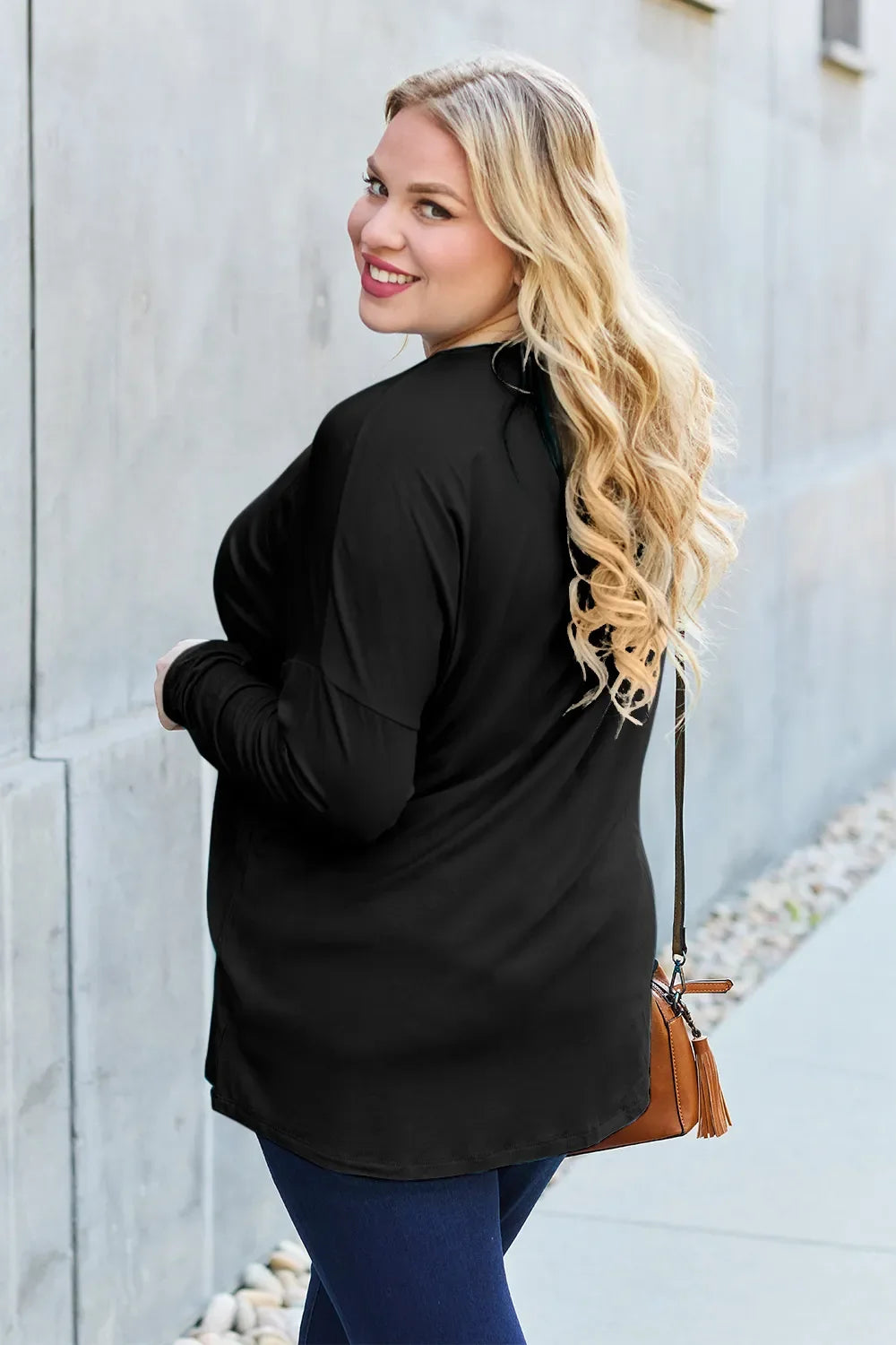 Black relaxed long sleeve crewneck tee, side view with curved hem