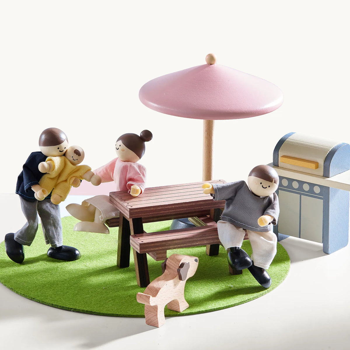 Pink dollhouse outdoor play area with table, tree, bench, and tiny figures