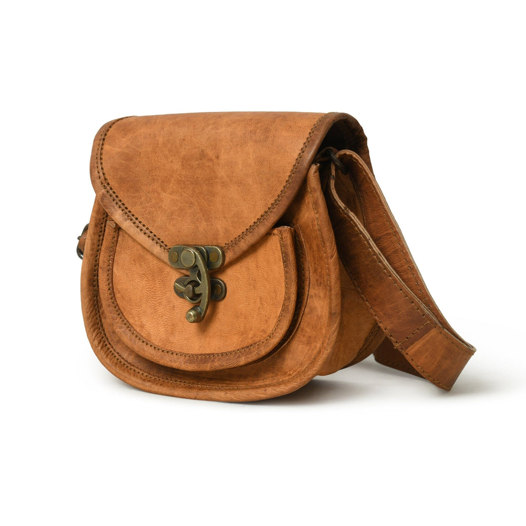 Tan leather crossbody sling bag with flap top, greenish hardware, and stitched edges