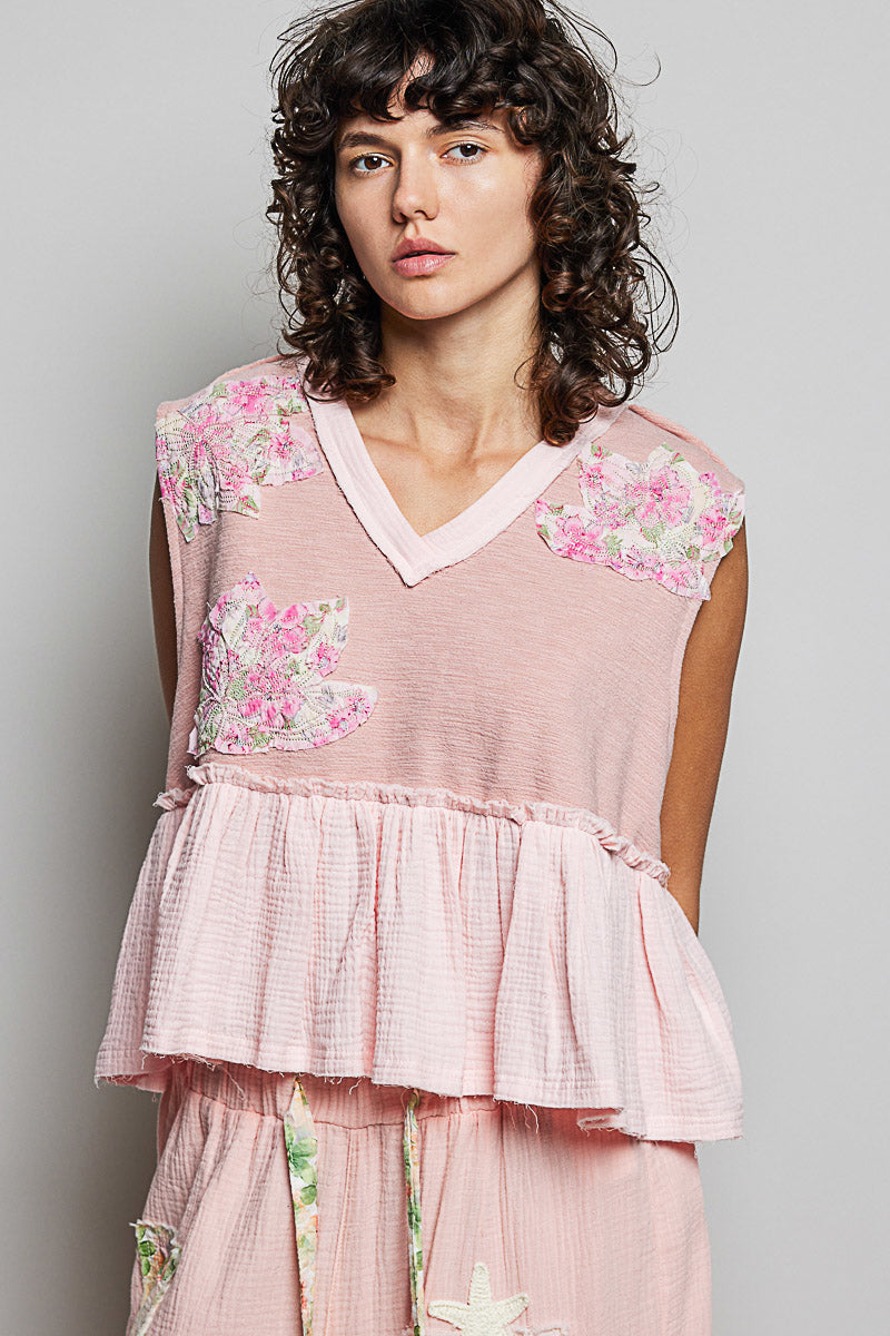 Pink sleeveless peplum top with floral patch accents, V-neck, and ruffled waist detail