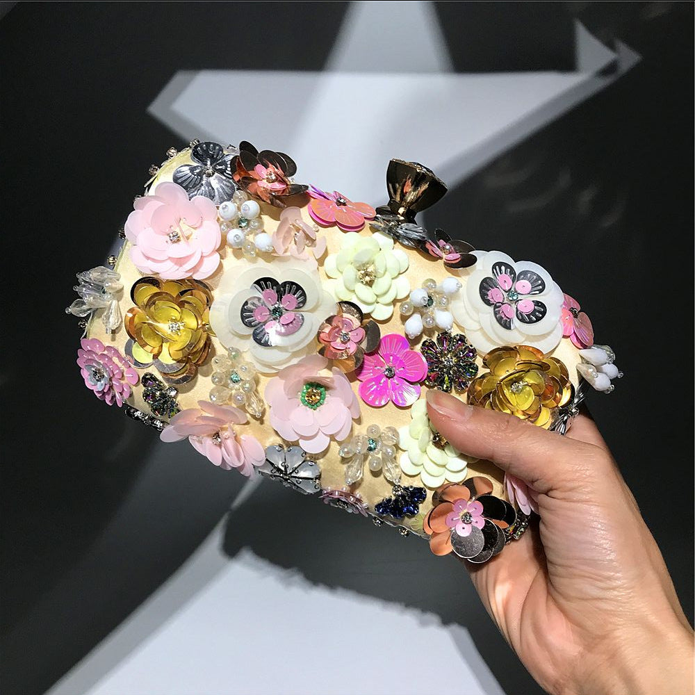 Colorful floral sequin clutch purse close-up, hand holding by the front embellished panel