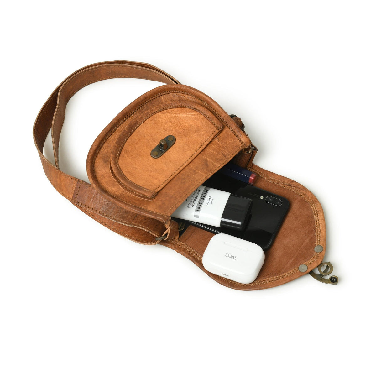 Tan leather crossbody sling bag with open interior holding phone and small items