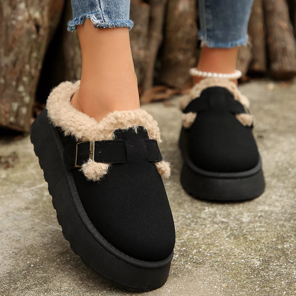 Black platform slippers with fuzzy trim, buckle strap, and thick sole