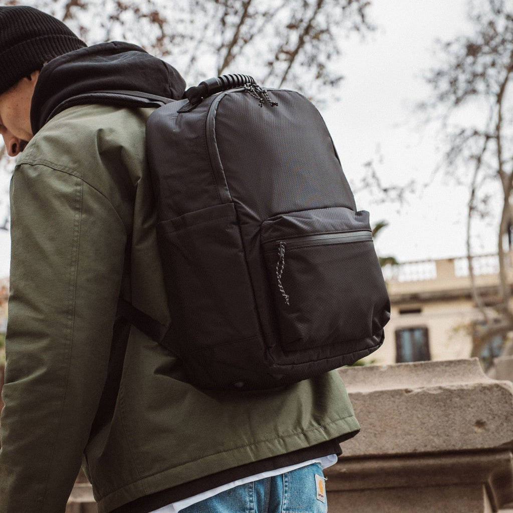 Dark gray-green backpack with front zip pocket and padded side panel.