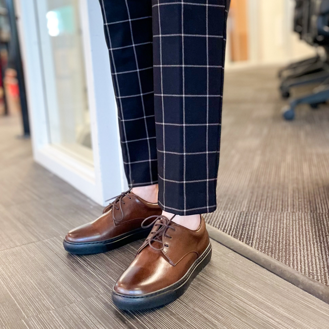 Brown lace-up dress shoes with blue-toned heel trim on a wood floor