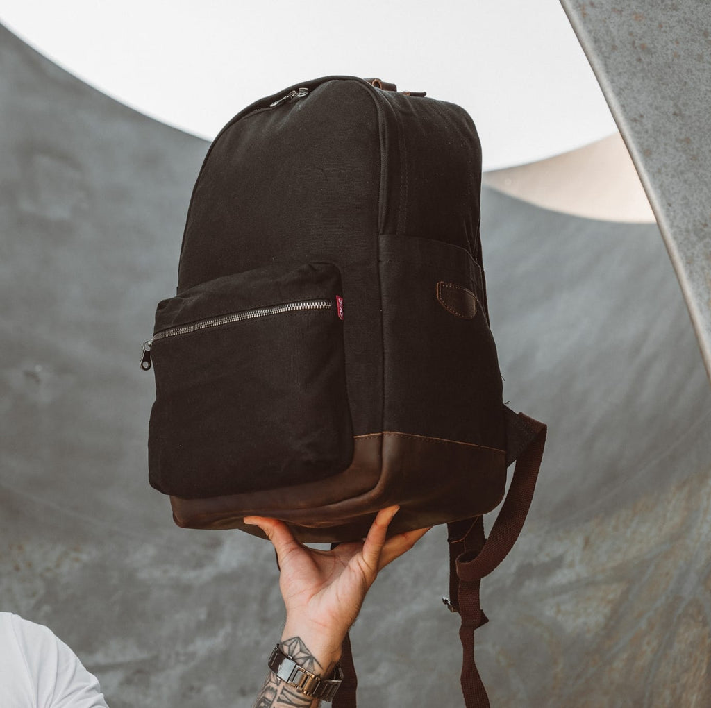 Dark brown canvas backpack with side pocket and top handle