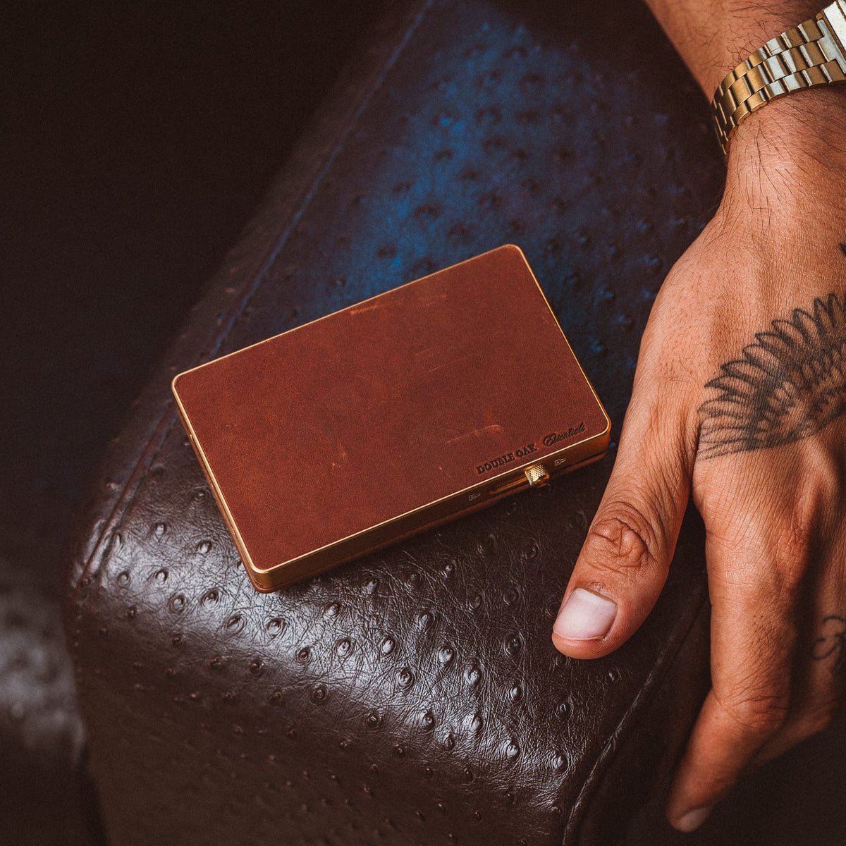 Brown leather mod wallet with gold trim, resting on dark leather surface