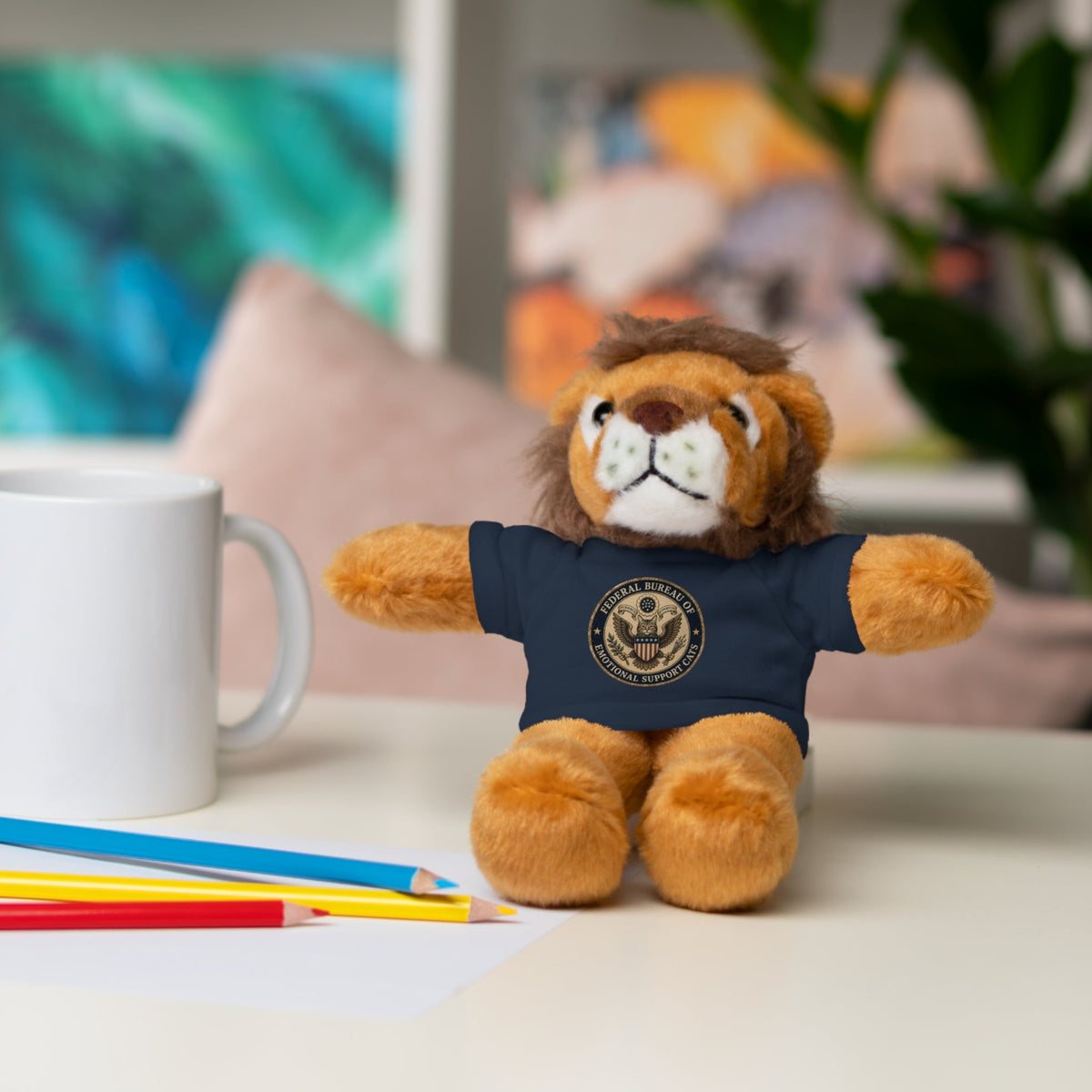 Lion plush toy with navy T-shirt and round emblem, sitting pose with friendly face