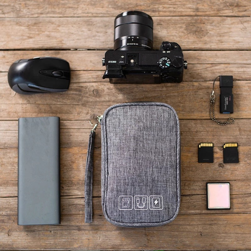 Gray cable organizer pouch laying open on the table with cables and small accessories inside.