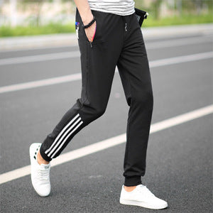 Men's black slim casual pants with white triple stripe detail on the side