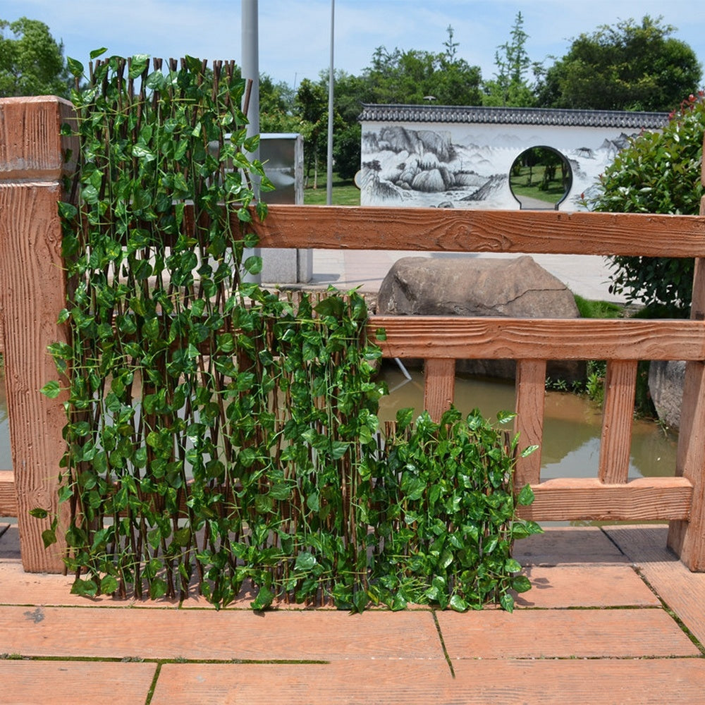 Expandable wooden plant trellis fence with green leaves and a brown wooden frame