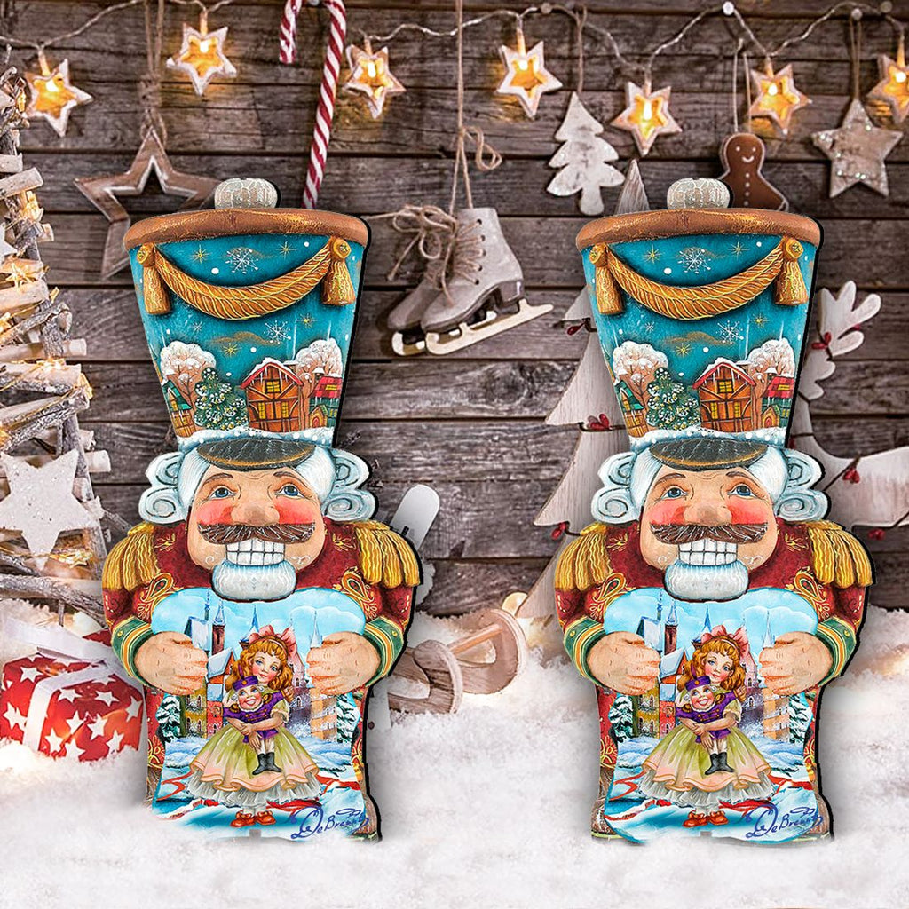 Two painted nutcracker holiday figures with blue tops, red coats, holding dolls
