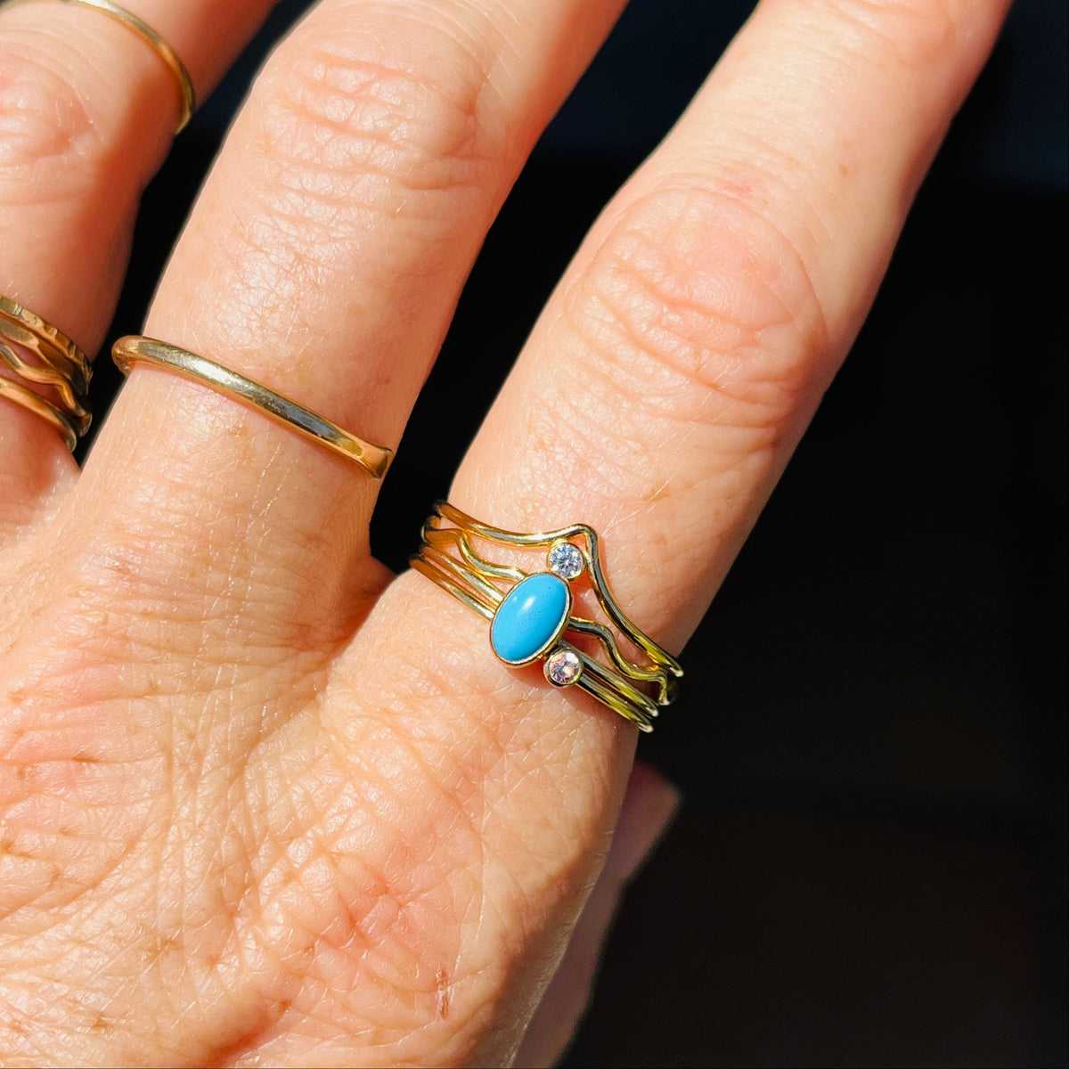 Gold-tone wave ring with oval turquoise cabochon and small clear stone accents