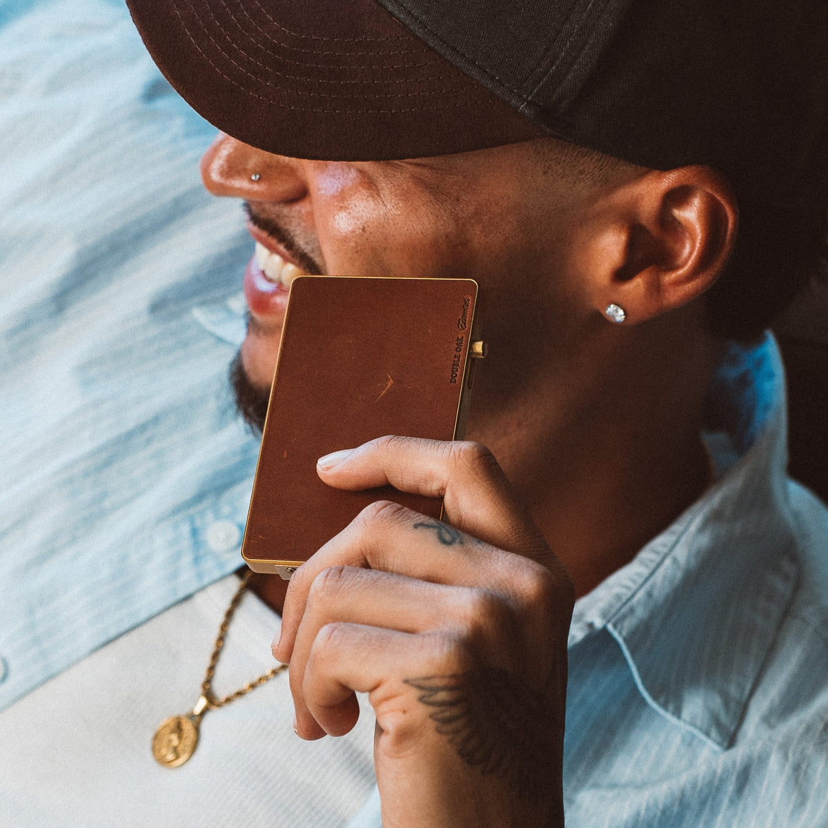 Brown leather card mod wallet with gold trim, opened and held by hand