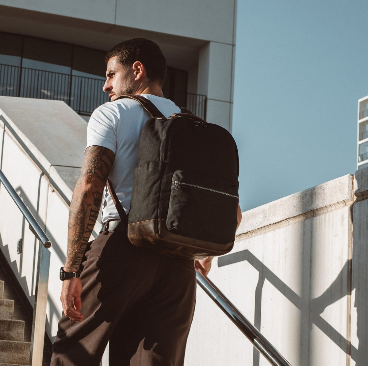 Black backpack with leather shoulder straps, top handle, and front zipper