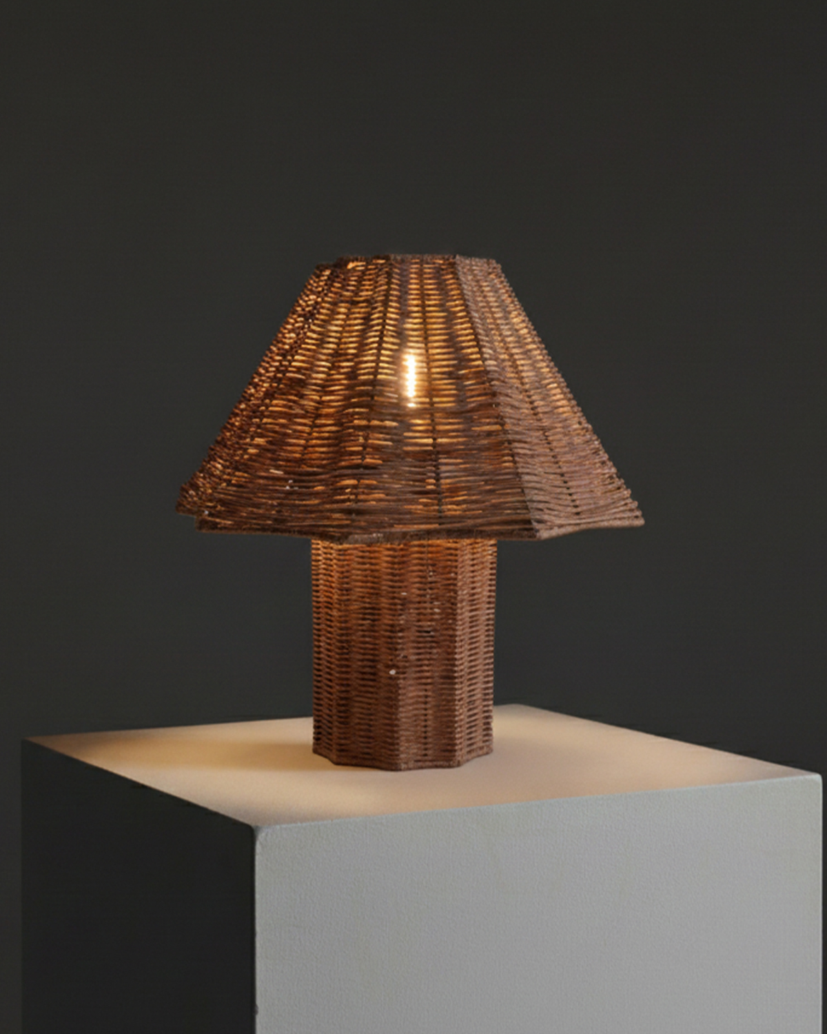 Woven rattan table lamp with lit conical shade and cylindrical base