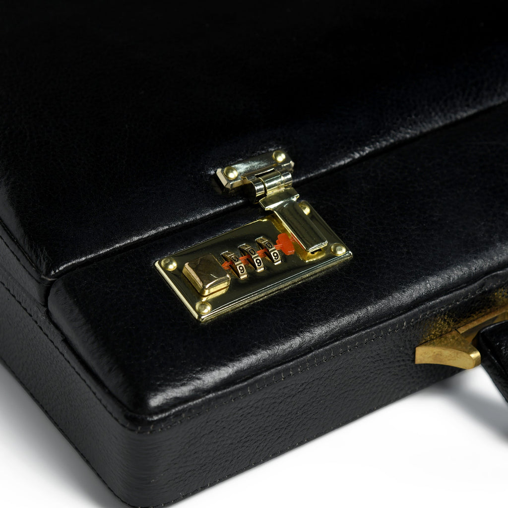 Close-up of black briefcase lock with gold-tone keypad and clasp