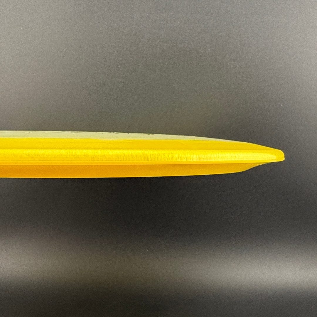Yellow disc golf disc side view with thin outer rim profile