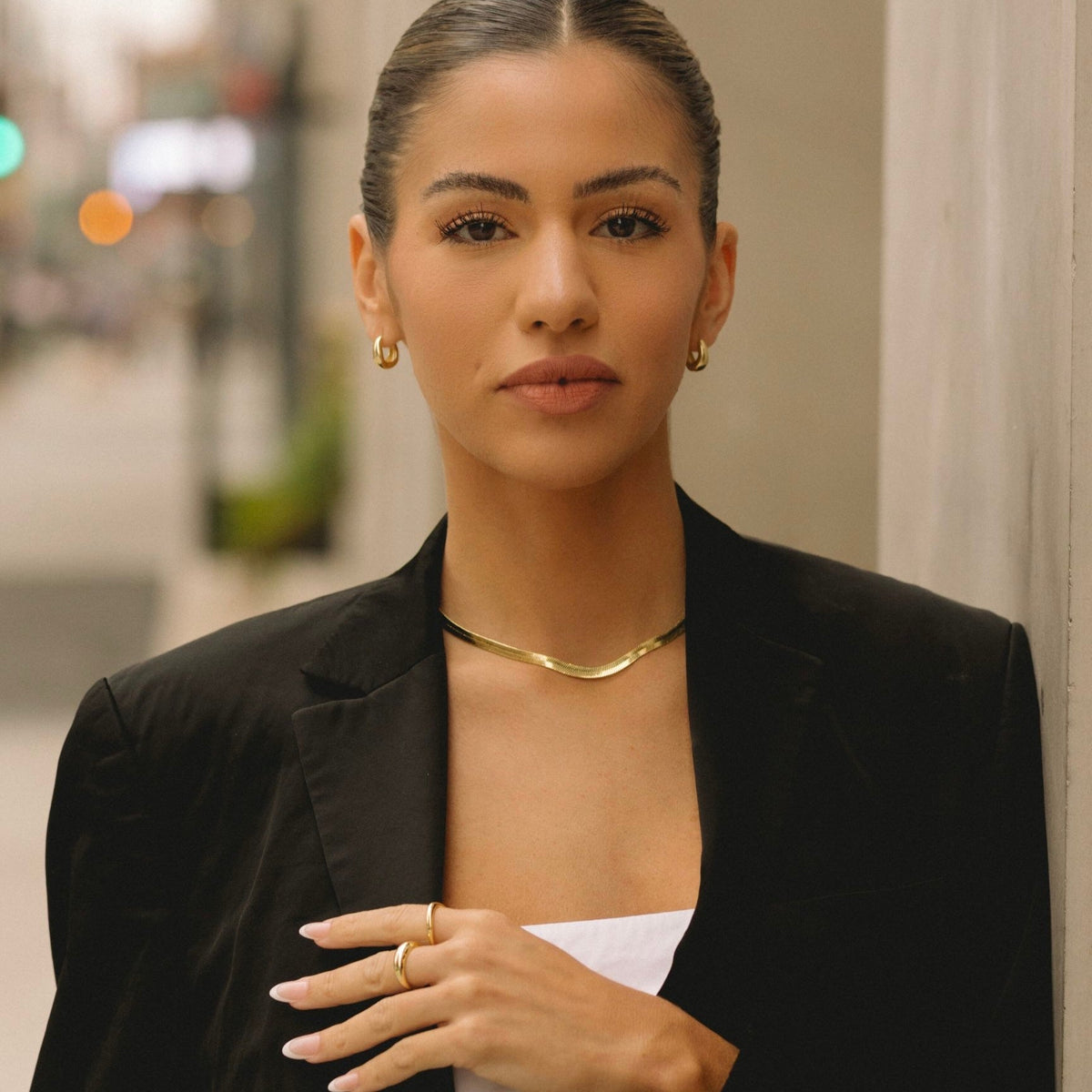 Gold herringbone chain necklace worn on the collarbone with a V-shaped drape