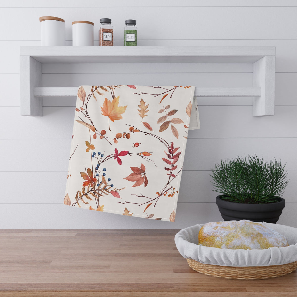 Fall foliage tea towel draped on a kitchen shelf with autumn leaf print