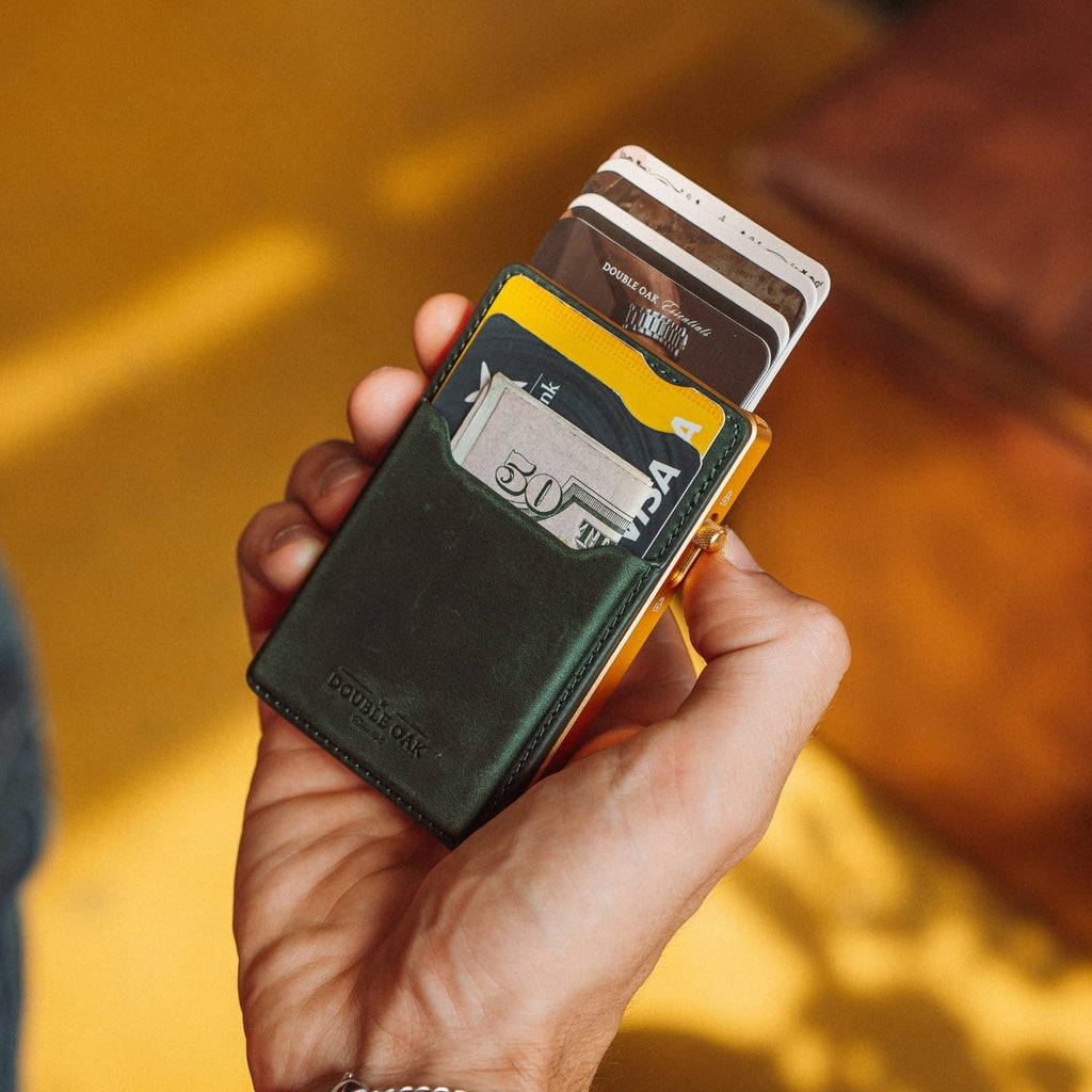 Dark green leather card mod wallet with cards in slot and gold-tone frame