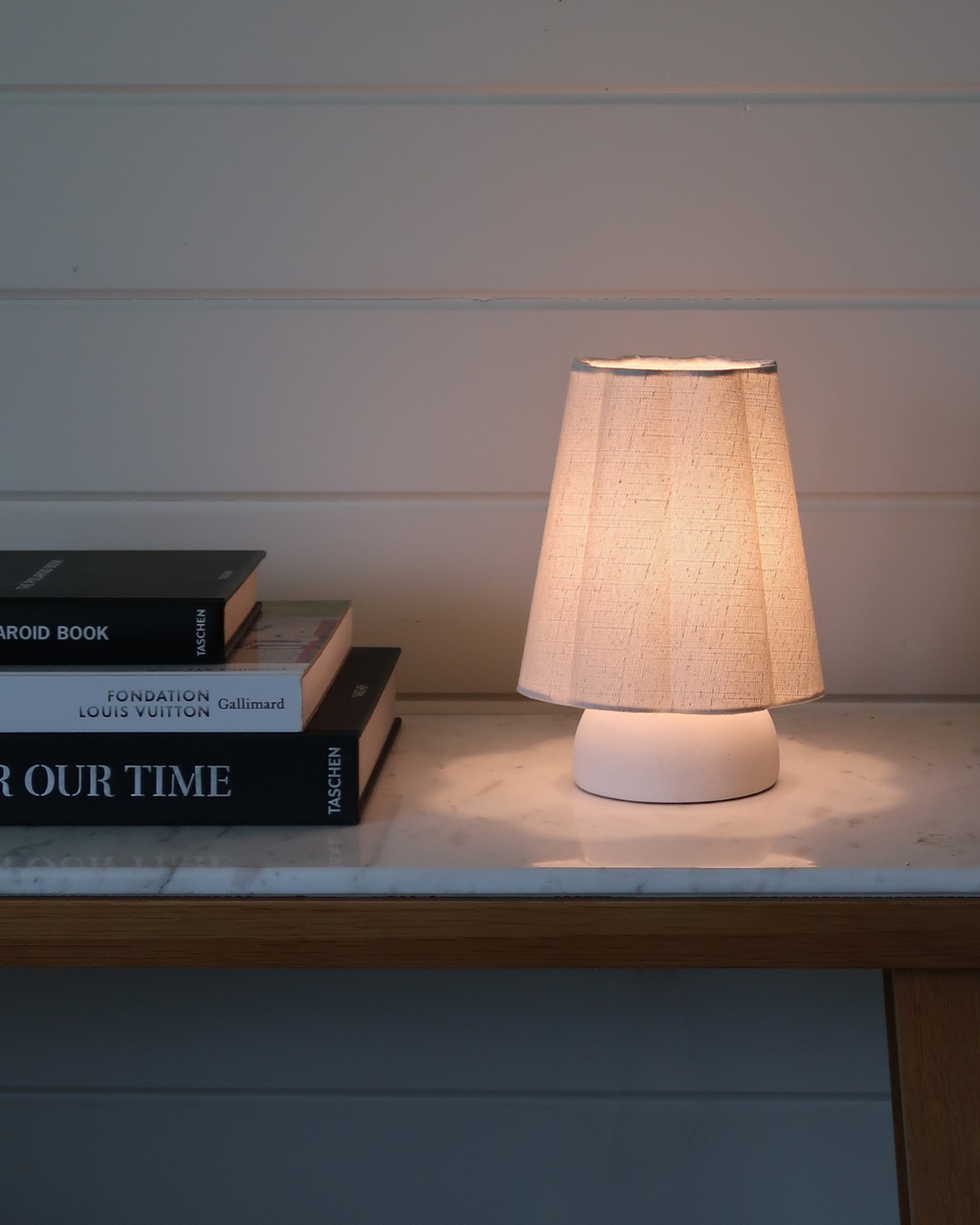 Table lamp with warm lit off-white drum shade and white round base