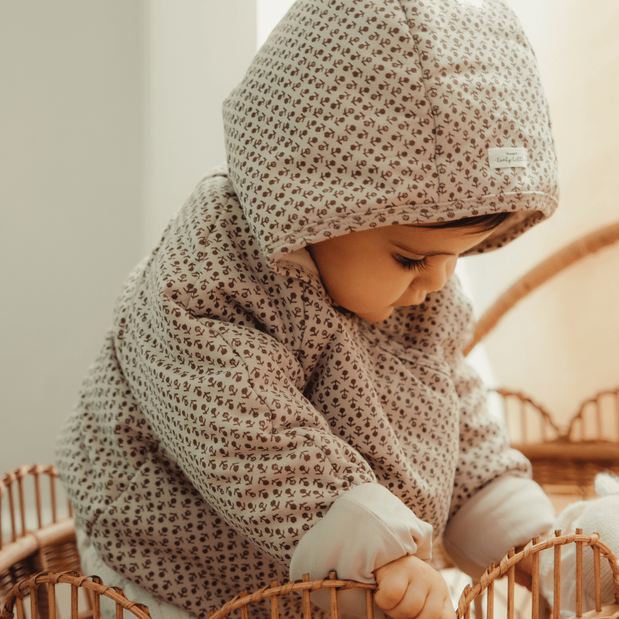 Light pink allover print baby jacket with hood and front pocket, worn by a child
