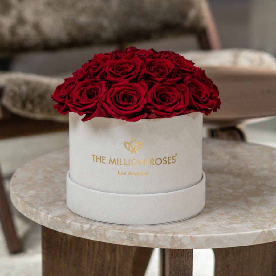 Beige dome box with red roses and gold logo, on side table