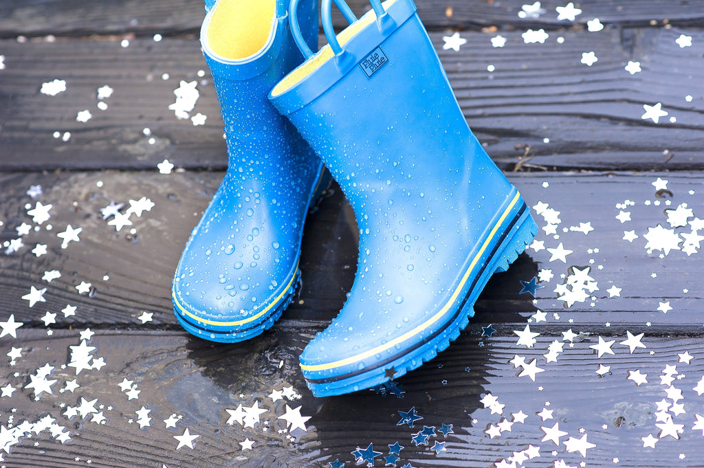 Blue rain boots with yellow trim on wet surface with water droplets