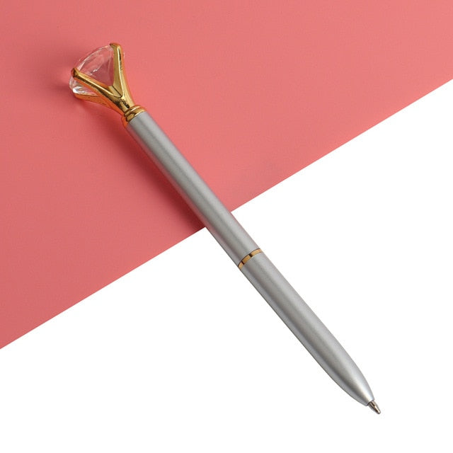Silver-colored ballpoint pen with faceted gold gem top and metal ballpoint tip