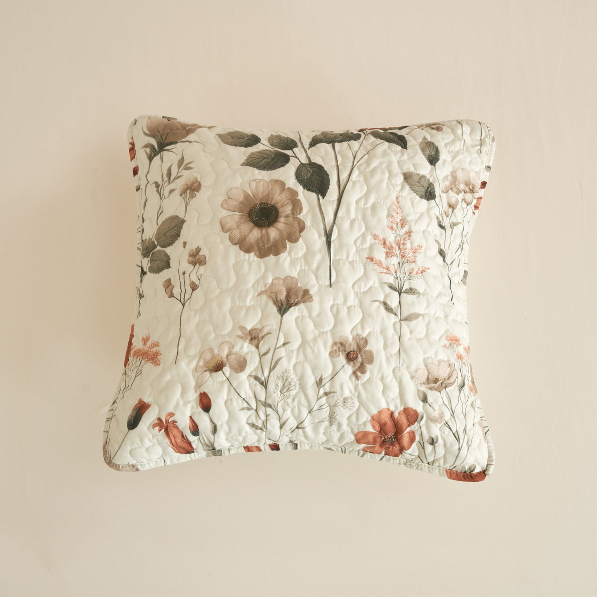 Floral quilt pillow in off-white with dense quilting and botanical print in beige and rose.